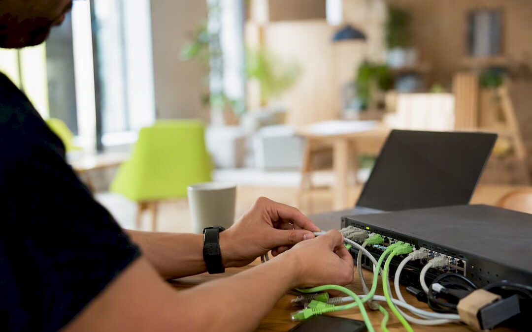 Hands connecting network cables in office