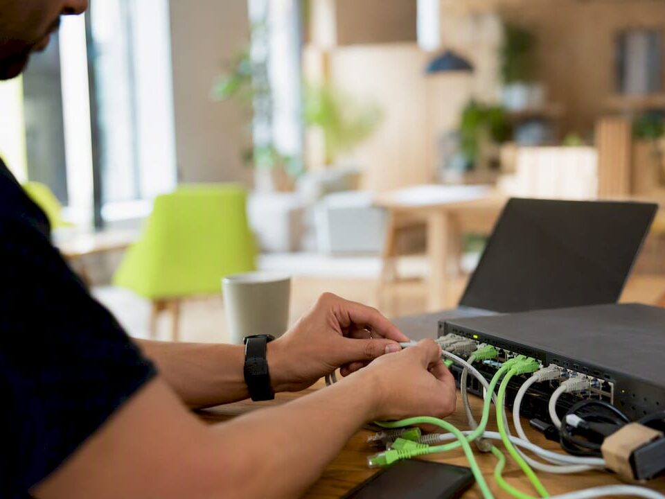 Hands connecting network cables in office