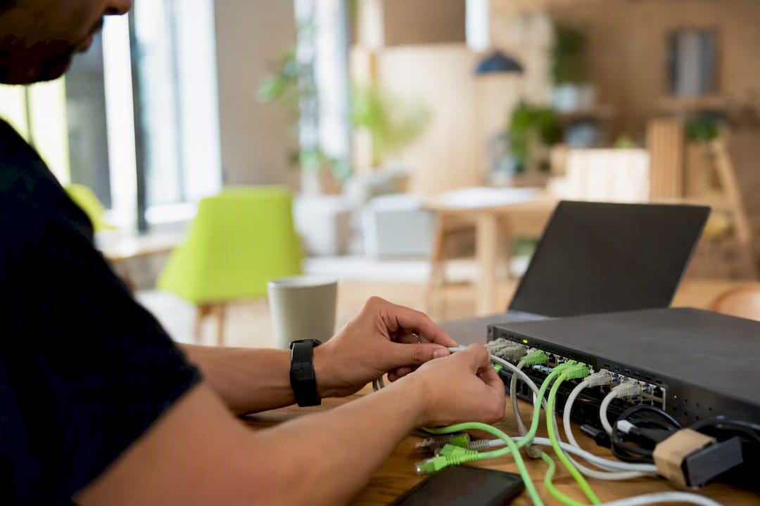 Hands connecting network cables in office
