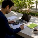 Hands calculating ROI on SME finance desk